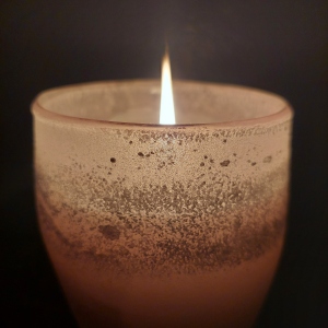 Photo of a lit candle against a dark background.