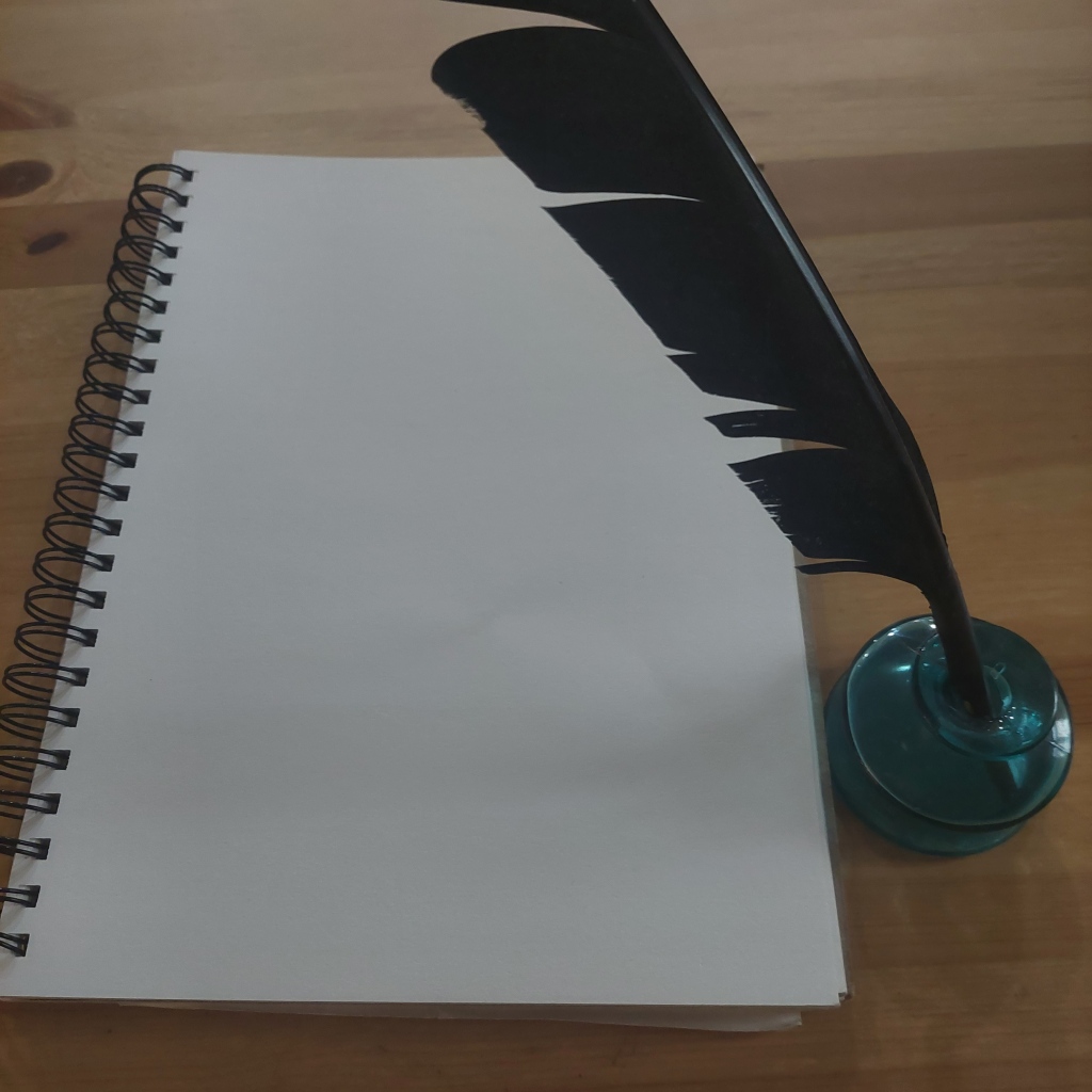 A quill in an empty inkwell positioned next to a blank notebook page.